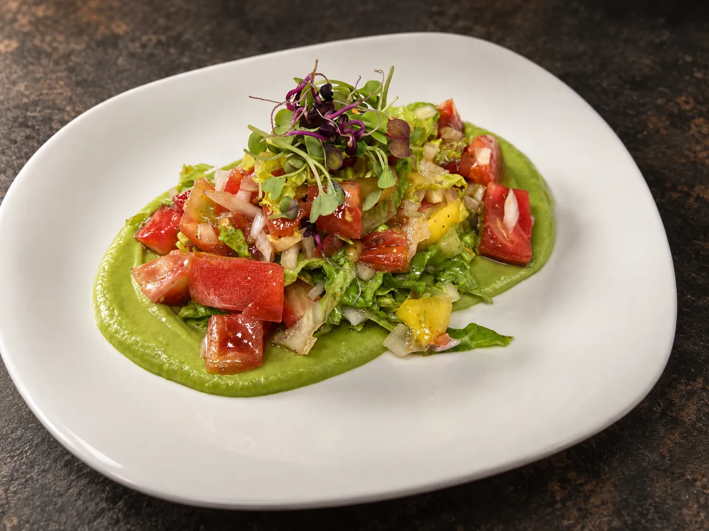Ensalada de mango y tomate rosa sobre crema de aguacate