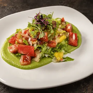 Ensalada de mango y tomate rosa sobre crema de aguacate cítrico