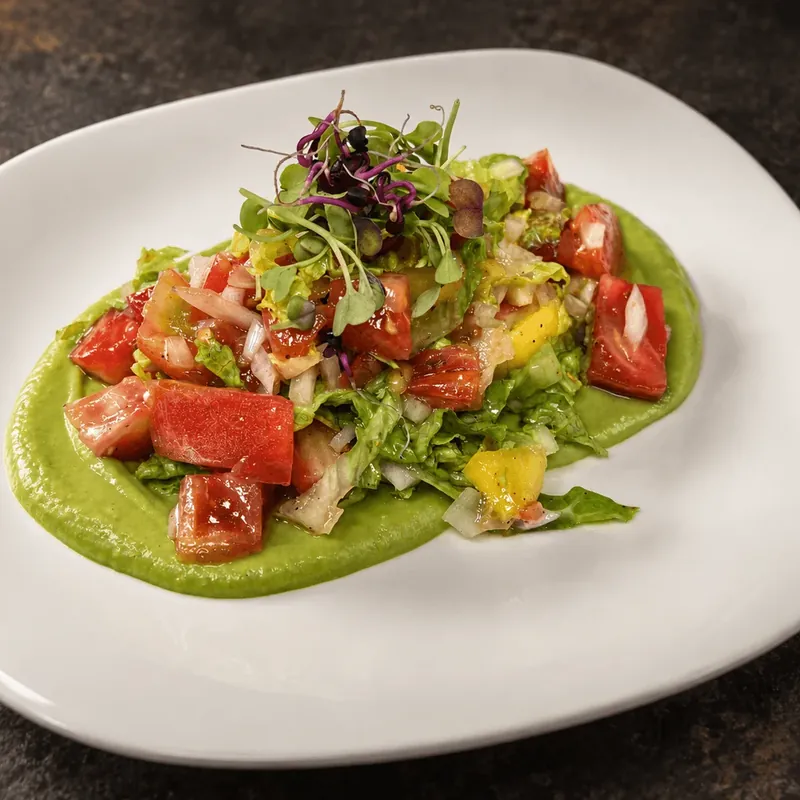 Ensalada de mango y tomate rosa sobre crema de aguacate cítrico