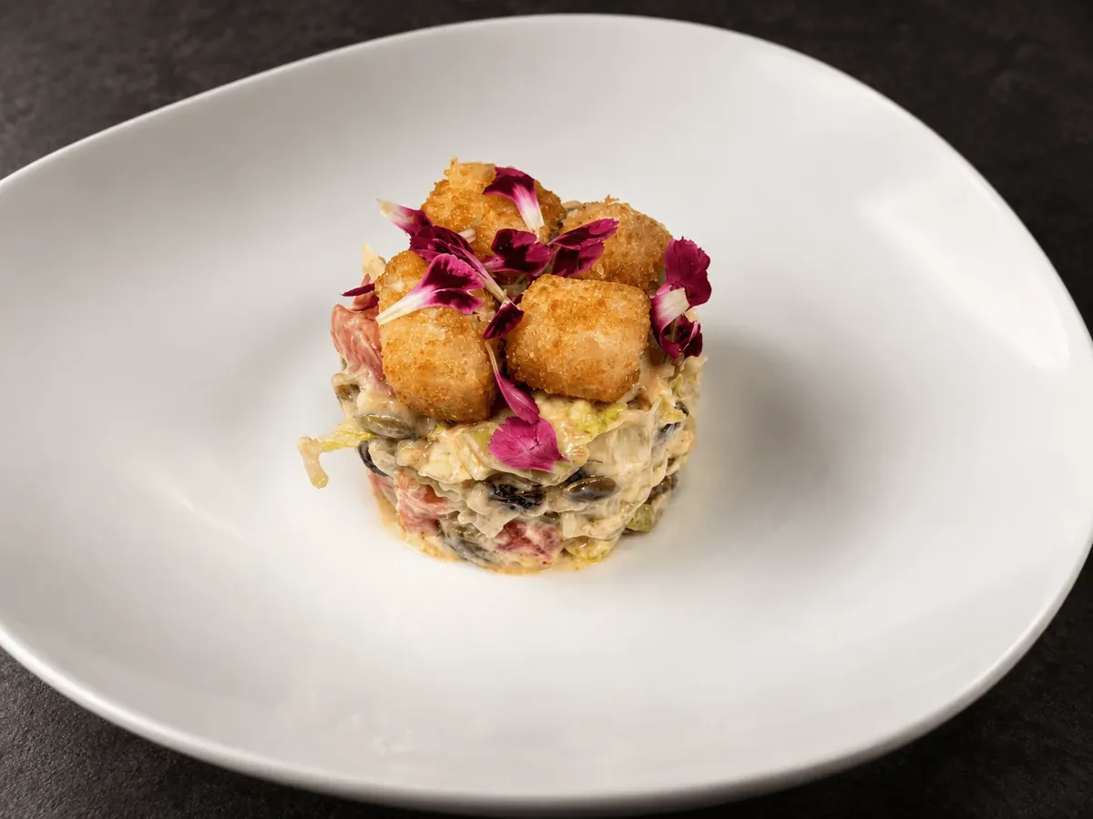 Ensalada templada de queso de cabra en aro, con flores comestibles