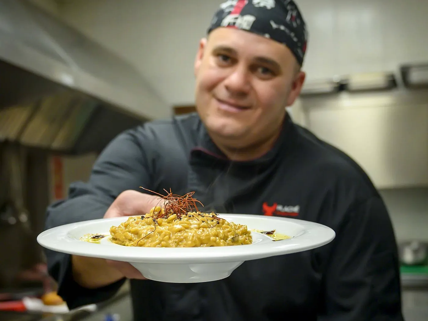 Cocinero de Plaché mostrando un plato recién emplatado en la cocina