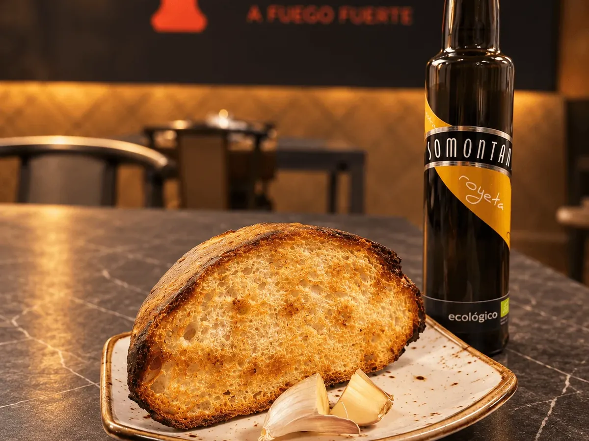 Rodaja de pan de masa madre tostado junto a una botella de aceite del Somontano