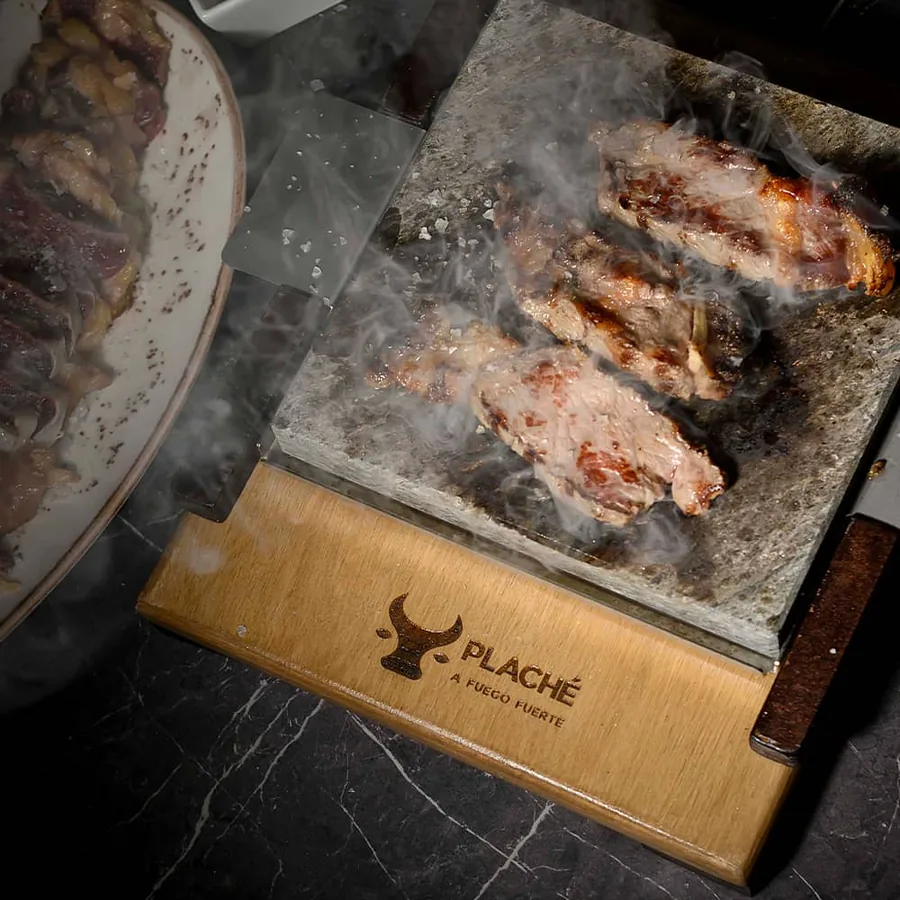 Carne a la piedra servida sobre la tabla grabada de Plaché