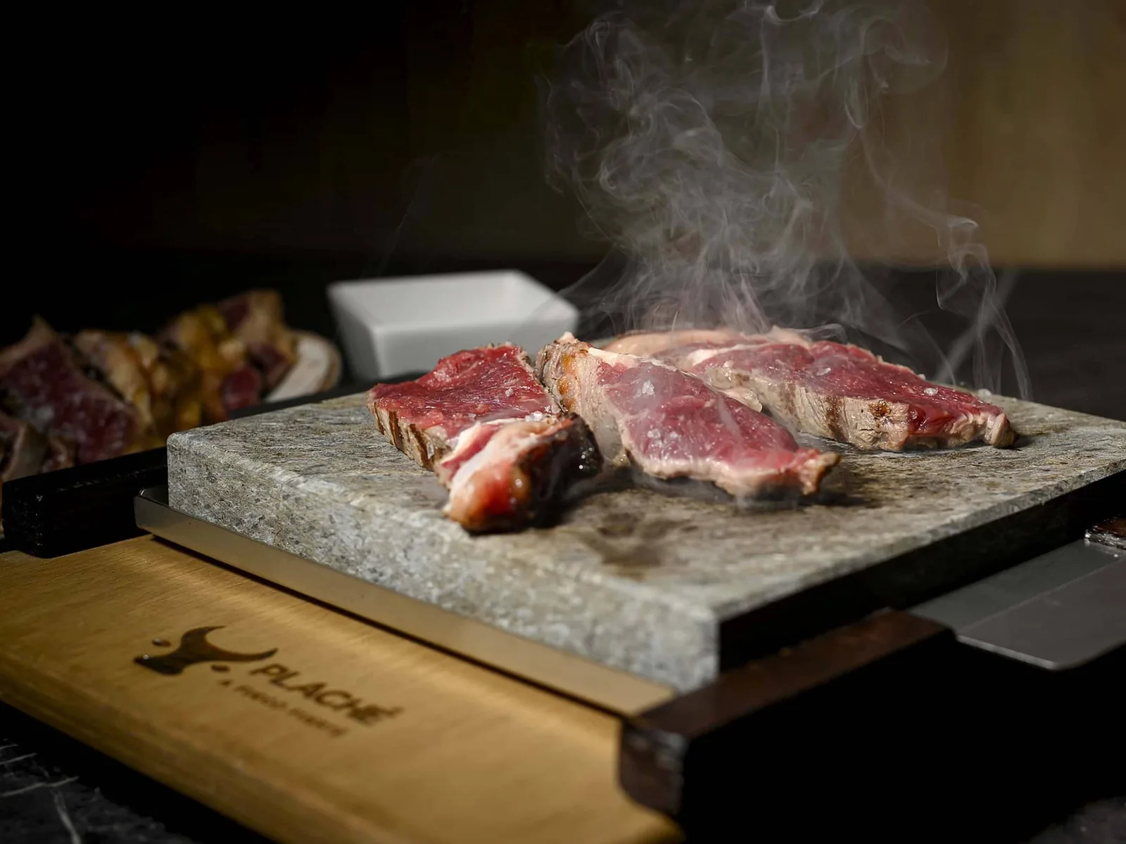 Cortes de carne sellándose sobre la piedra volcánica caliente de Plaché